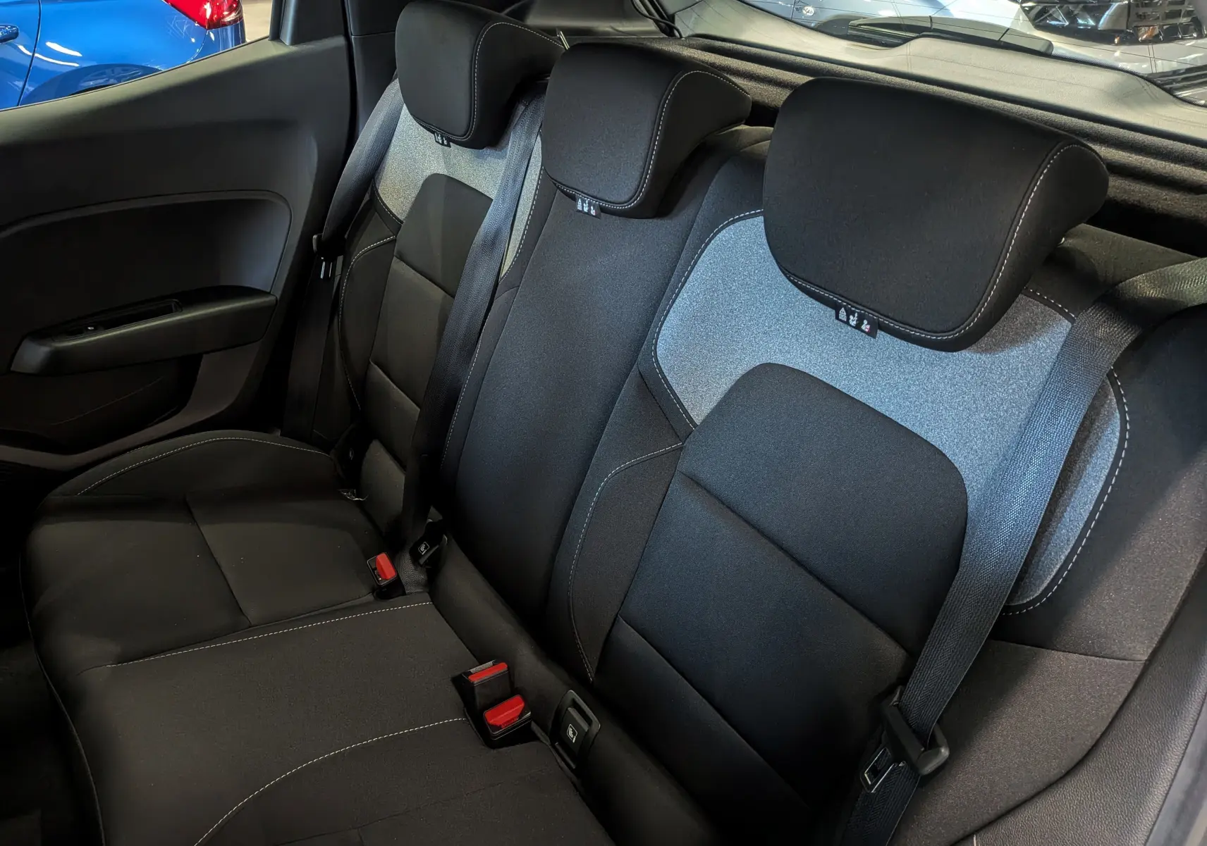 Vue intérieure des sièges arrière en tissu noir et gris d'une Renault Clio V 2025, avec ceintures de sécurité visibles.