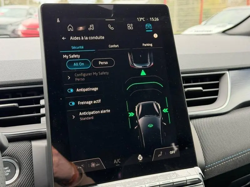 Écran tactile central du Renault Captur 2026 affichant les aides à la conduite, intérieur avec détails noirs et bleus.