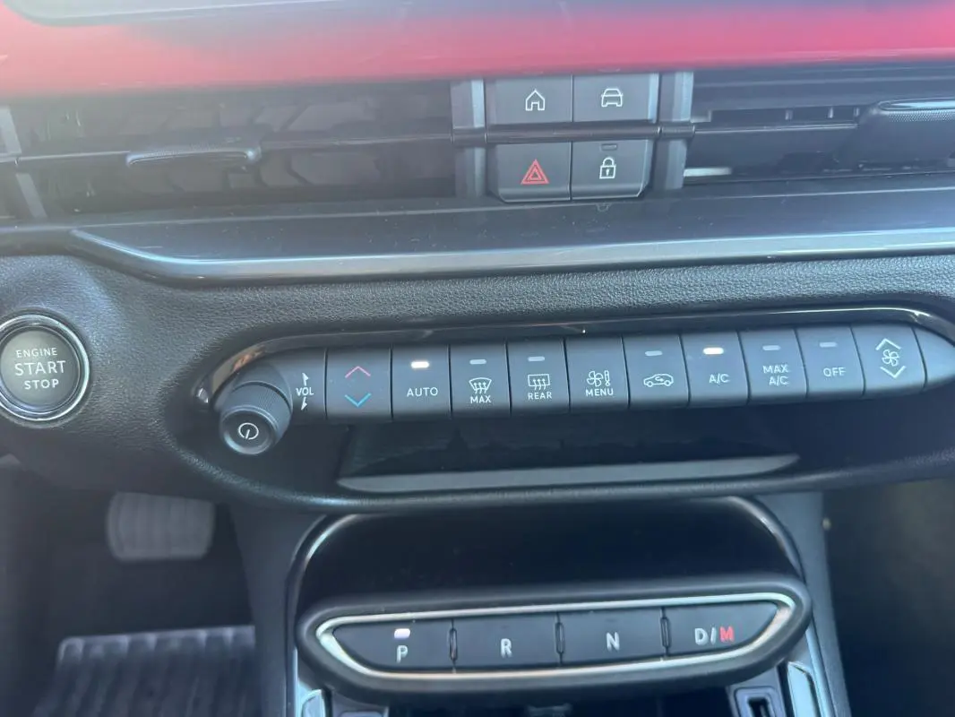 Vue rapprochée de la console centrale du Fiat 600 rouge 2025, montrant les commandes climatisation et boîte auto.