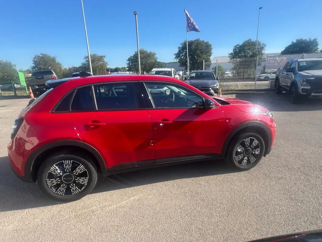 Vue de profil côté gauche d'une FIAT 600 T-Gen 3 rouge 2025 avec jantes noires au design graphique.