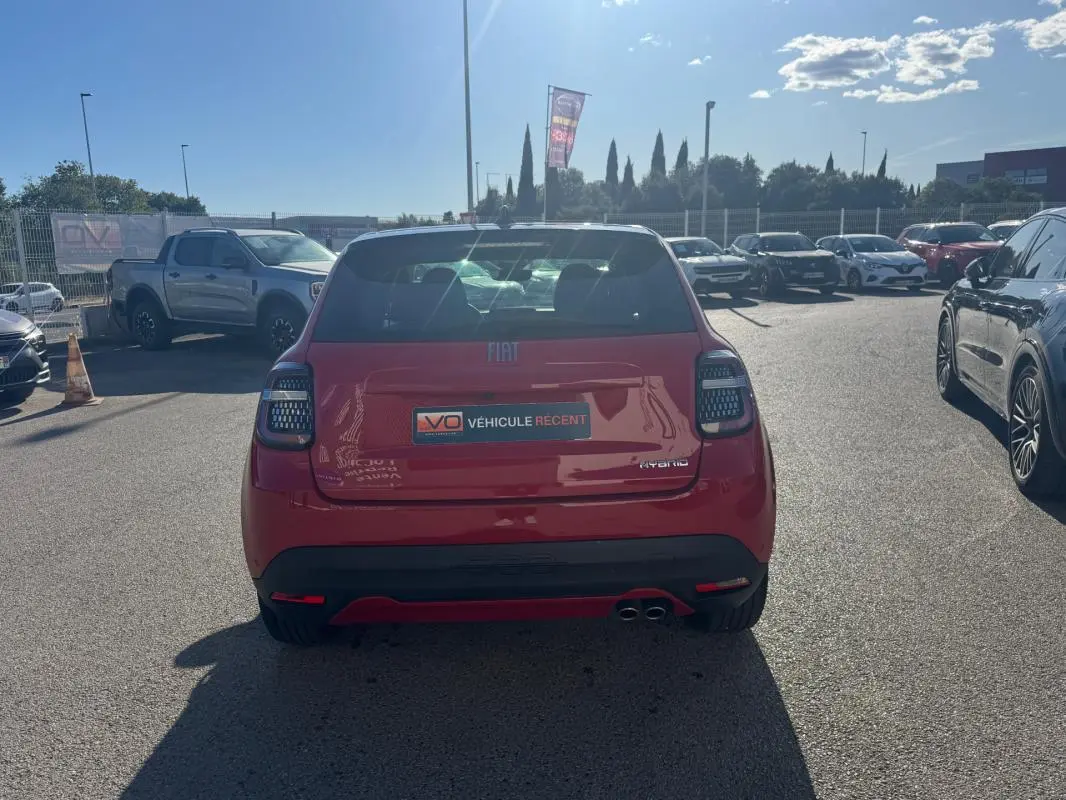 Vue arrière d'une FIAT 600 T-Gen 3 rouge 2025 avec double sortie d'échappement et feux arrière LED en parking extérieur.