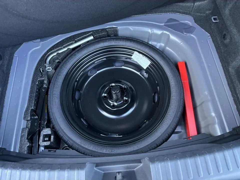 Vue plongeante sur la roue de secours noire dans le coffre d'une CUPRA Leon 2024 gris Graphene.