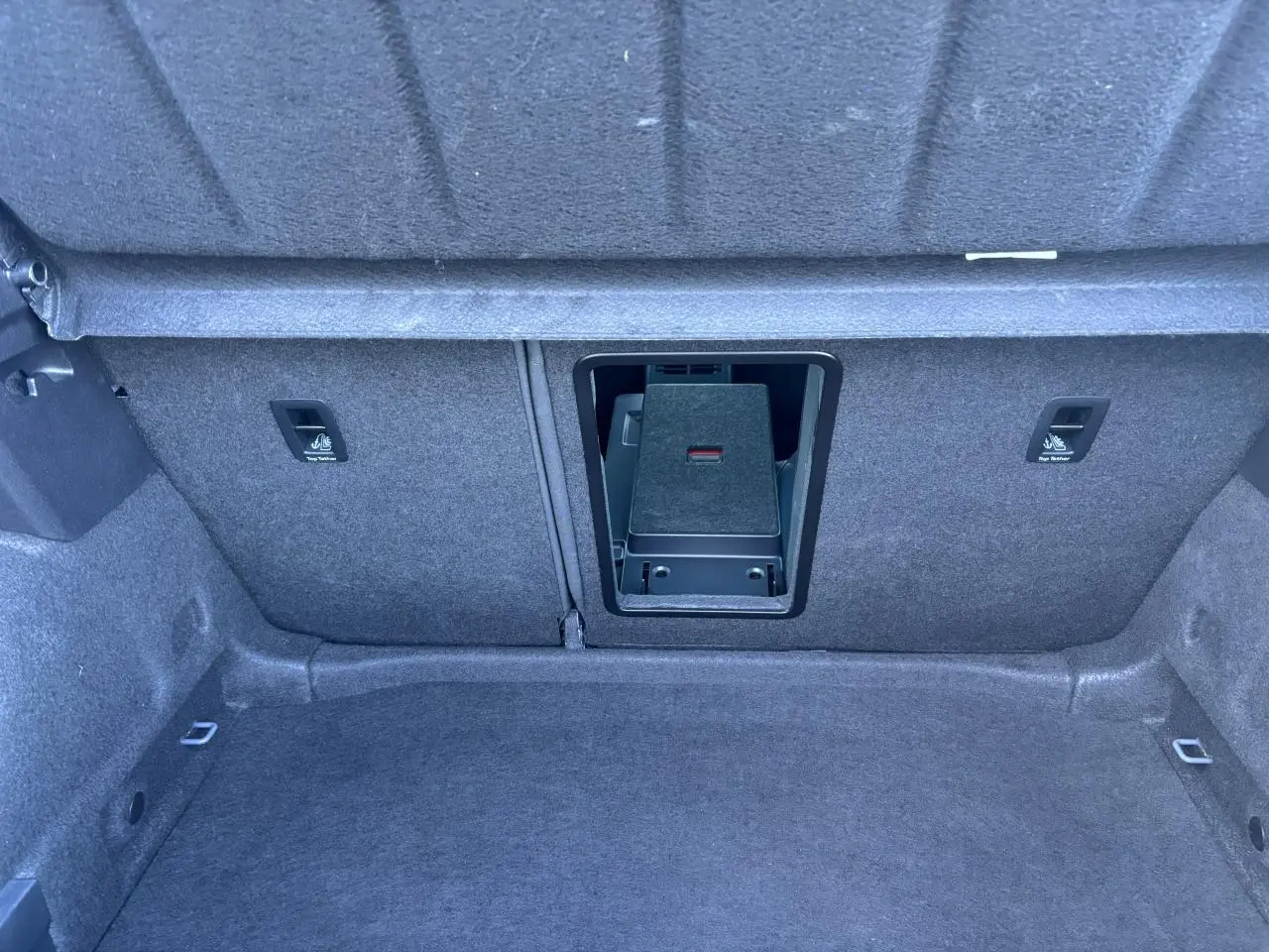 Vue intérieure du coffre du CUPRA Leon 2024 gris Graphene, montrant l'ouverture de la banquette arrière et les fixations Isofix.