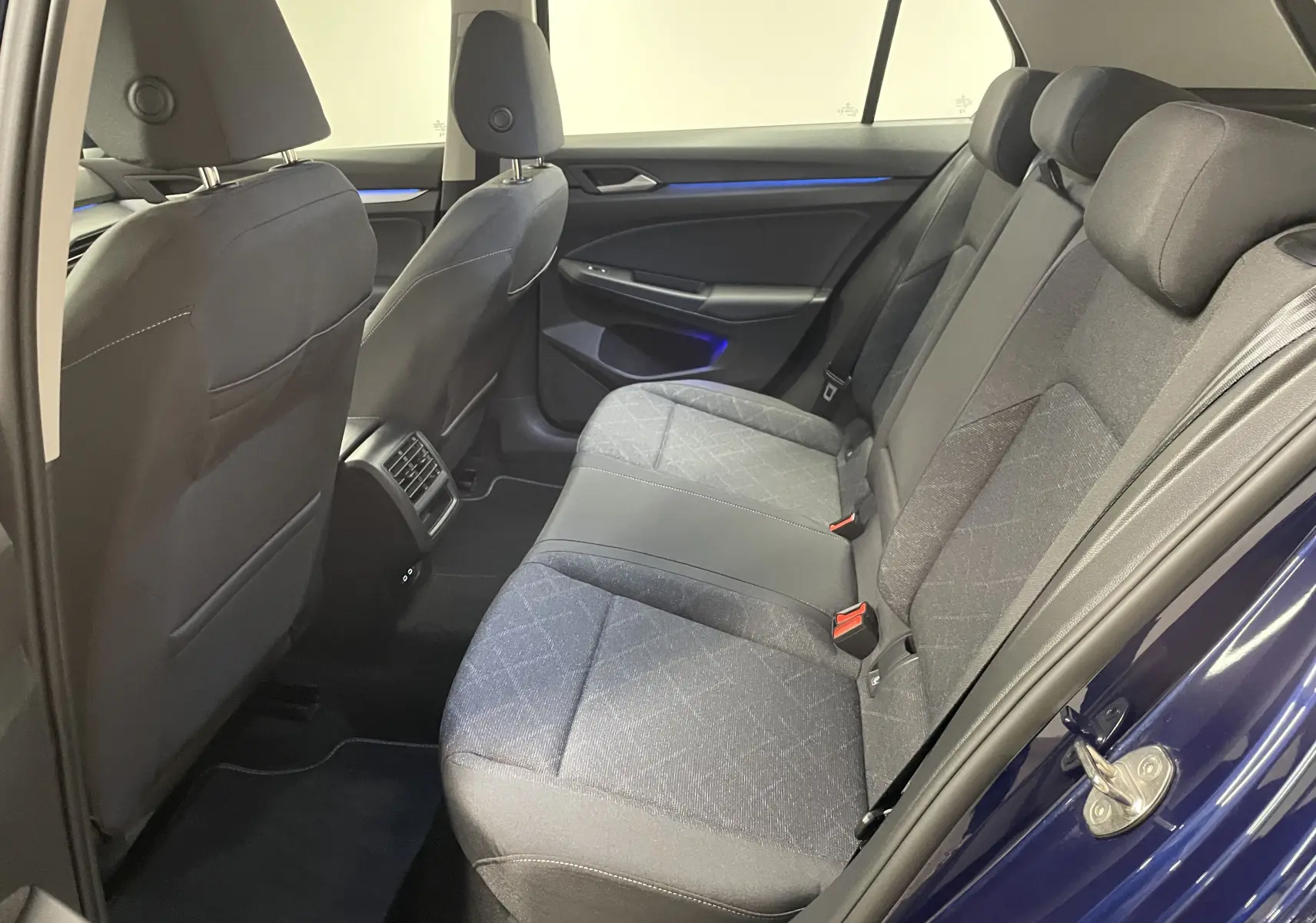 Vue intérieure arrière droite de la Volkswagen Golf 1.0 TSI 110 DSG7 Life Plus 2023 avec sièges tissu gris et portières Bleu Atlantique.