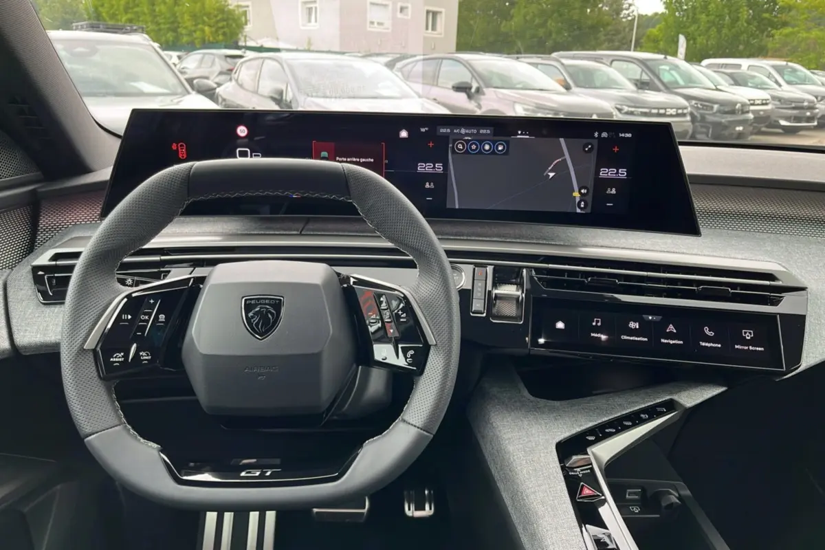 Vue intérieure du tableau de bord du Peugeot 5008 Hybrid 145 GT 2025, volant cuir multifonctions et écran digital large.