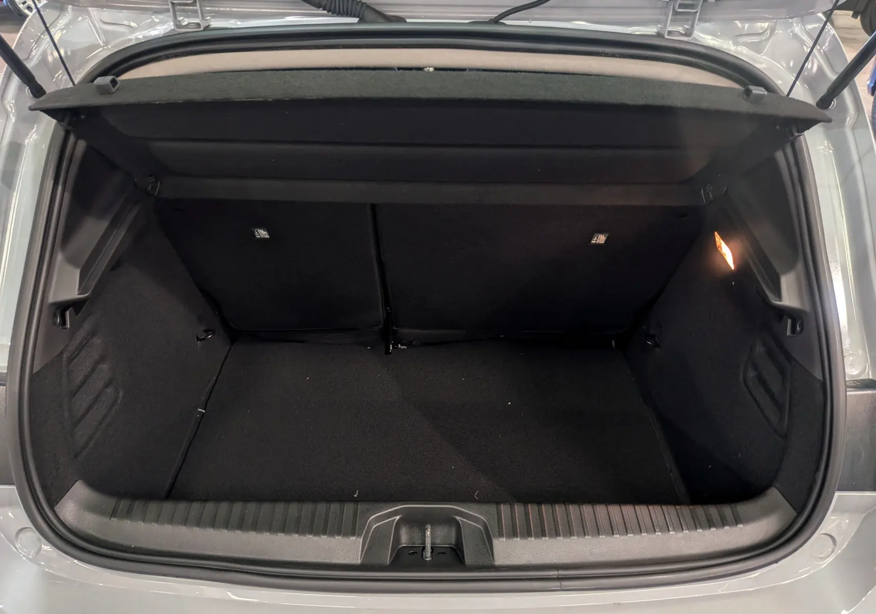 Coffre ouvert vu de l'arrière d'une Renault Clio V gris Rafale, montrant l'espace de rangement intérieur vide.