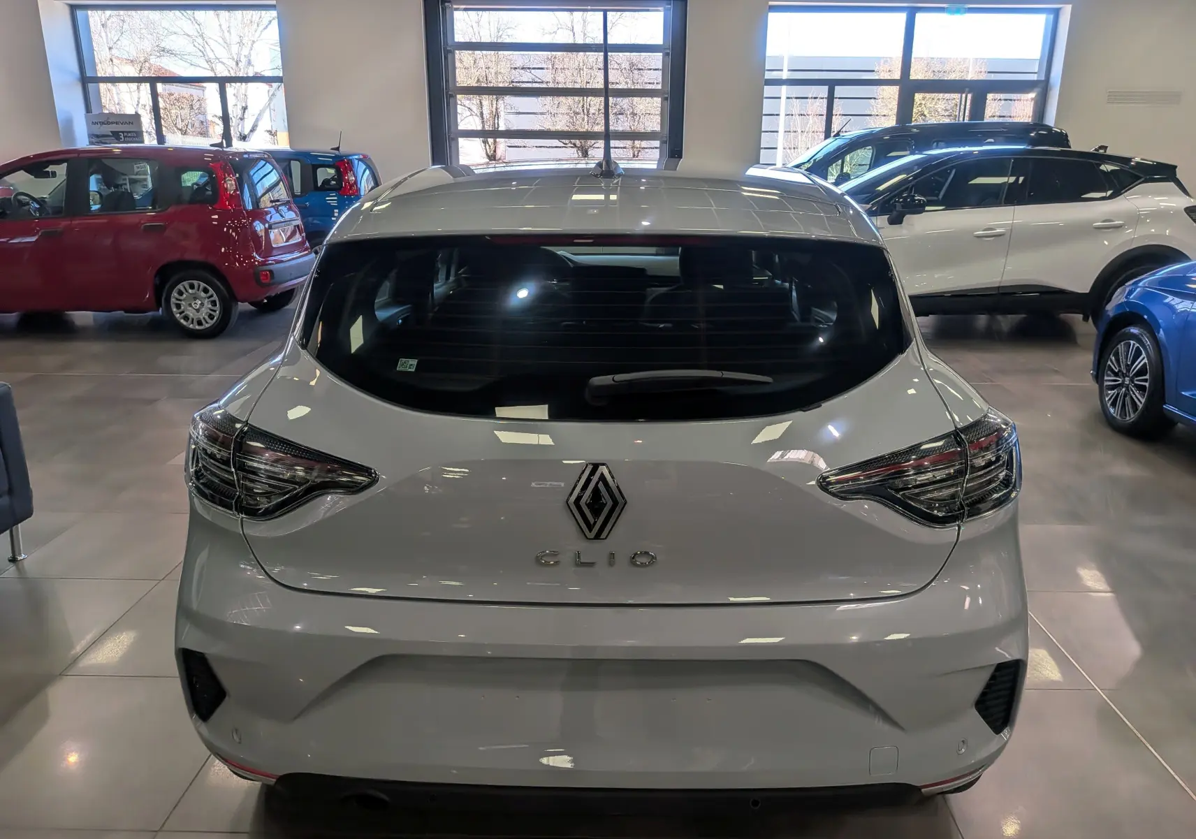 Vue arrière d'une Renault Clio V gris Rafale 2025, mettant en valeur ses feux arrière LED et son logo central.
