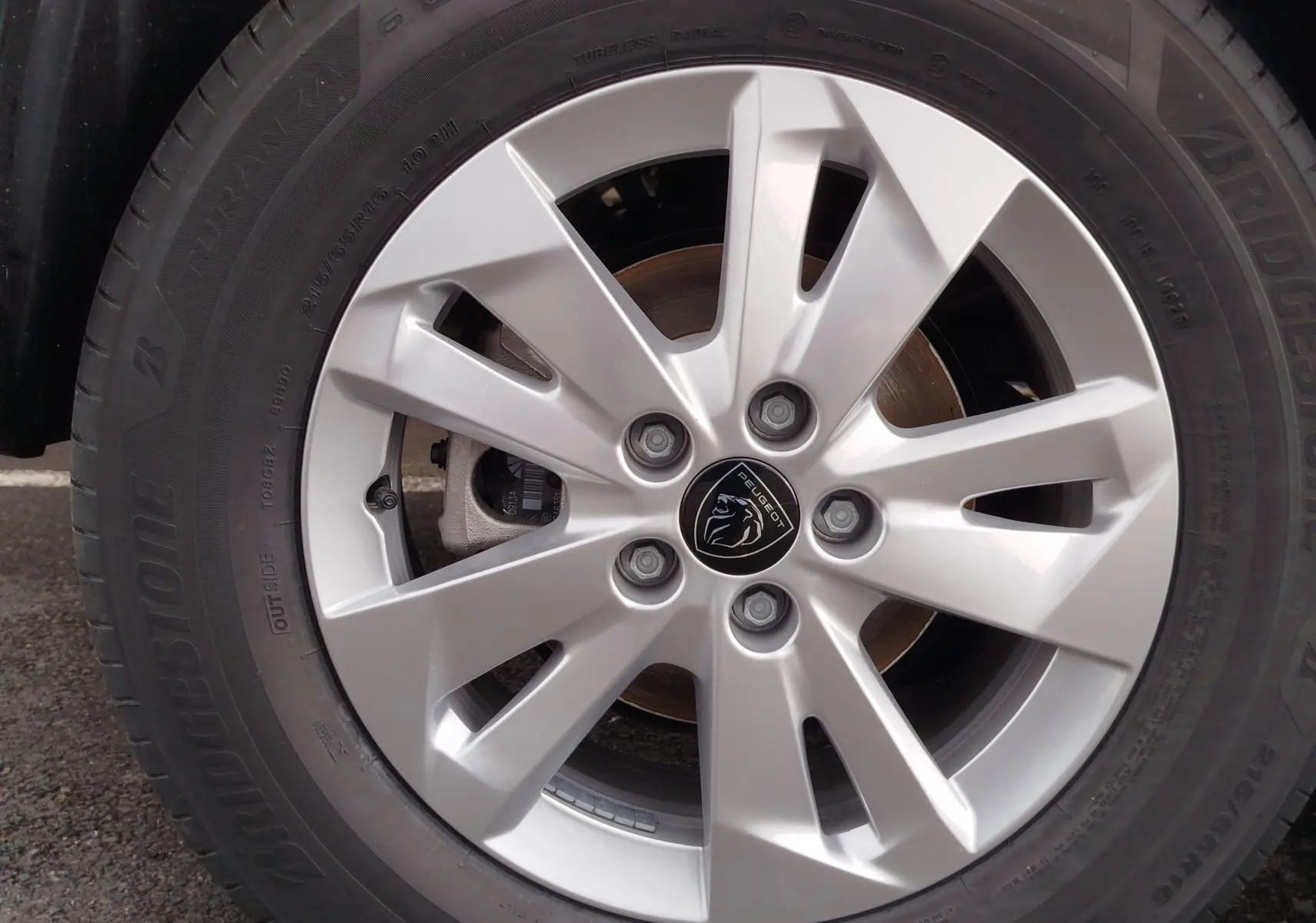 Gros plan sur la jante argentée du Peugeot Rifter 1.5 BlueHDi 130ch, avec logo lion au centre et pneu Bridgestone noir.
