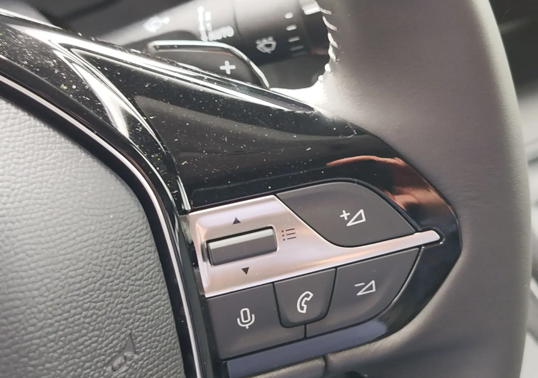 Gros plan sur les commandes au volant côté gauche du Peugeot Rifter 2026, finition noire brillante avec boutons multifonctions.
