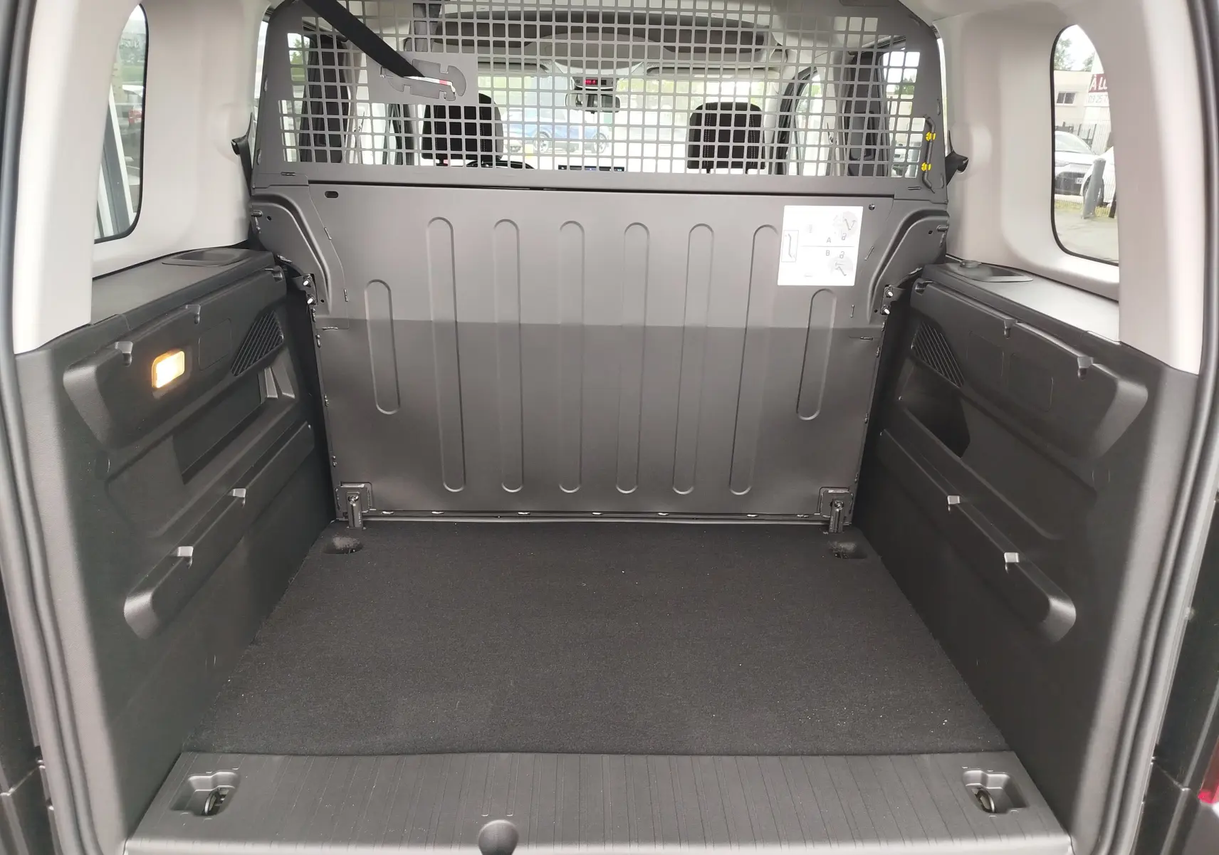 Vue intérieure du coffre spacieux du Peugeot Rifter noir Perla Nera, avec séparation métallique et aménagements latéraux.