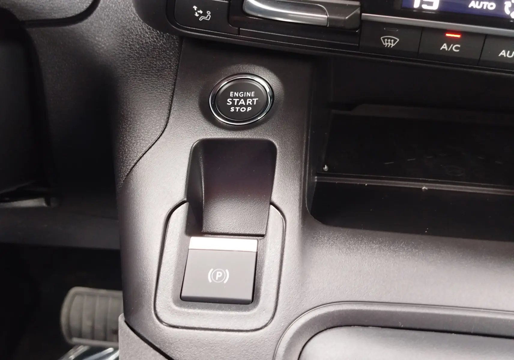 Gros plan intérieur sur le bouton start/stop et la commande de frein à main électronique du Peugeot Rifter noir Perla Nera.