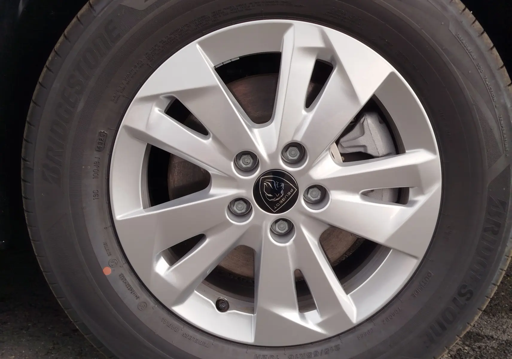 Gros plan sur la jante argentée du Peugeot Rifter 2026, mettant en valeur le logo central et le pneu Bridgestone noir.