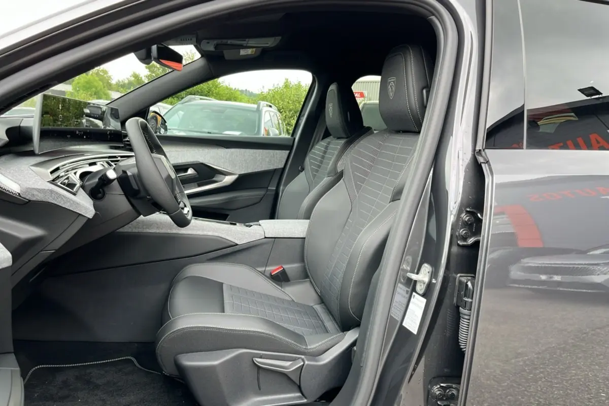 Vue intérieure côté conducteur du Peugeot 5008 Hybrid 145 GT 2025, sièges cuir gris avec logo Peugeot brodé.