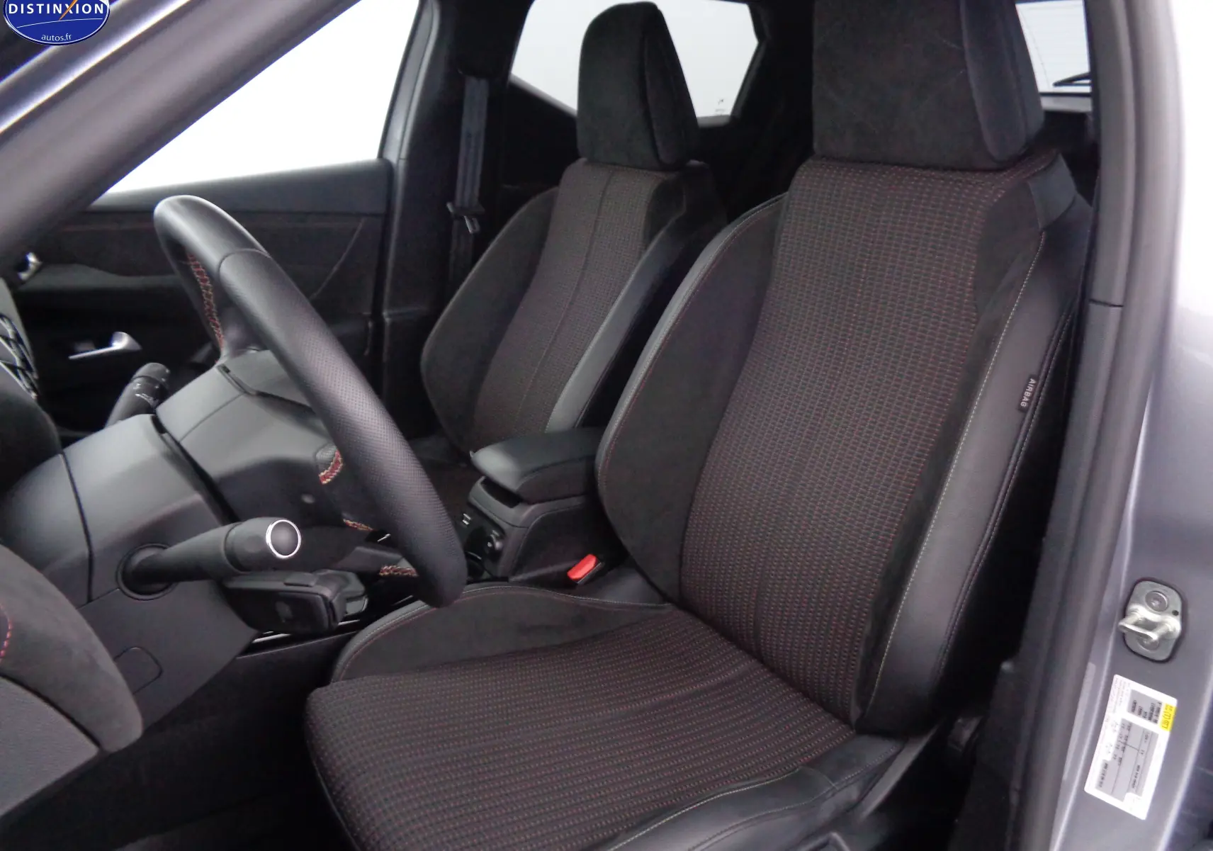 Vue intérieure côté conducteur du DS3 Crossback gris Artense, sièges en tissu noir avec surpiqûres rouges.