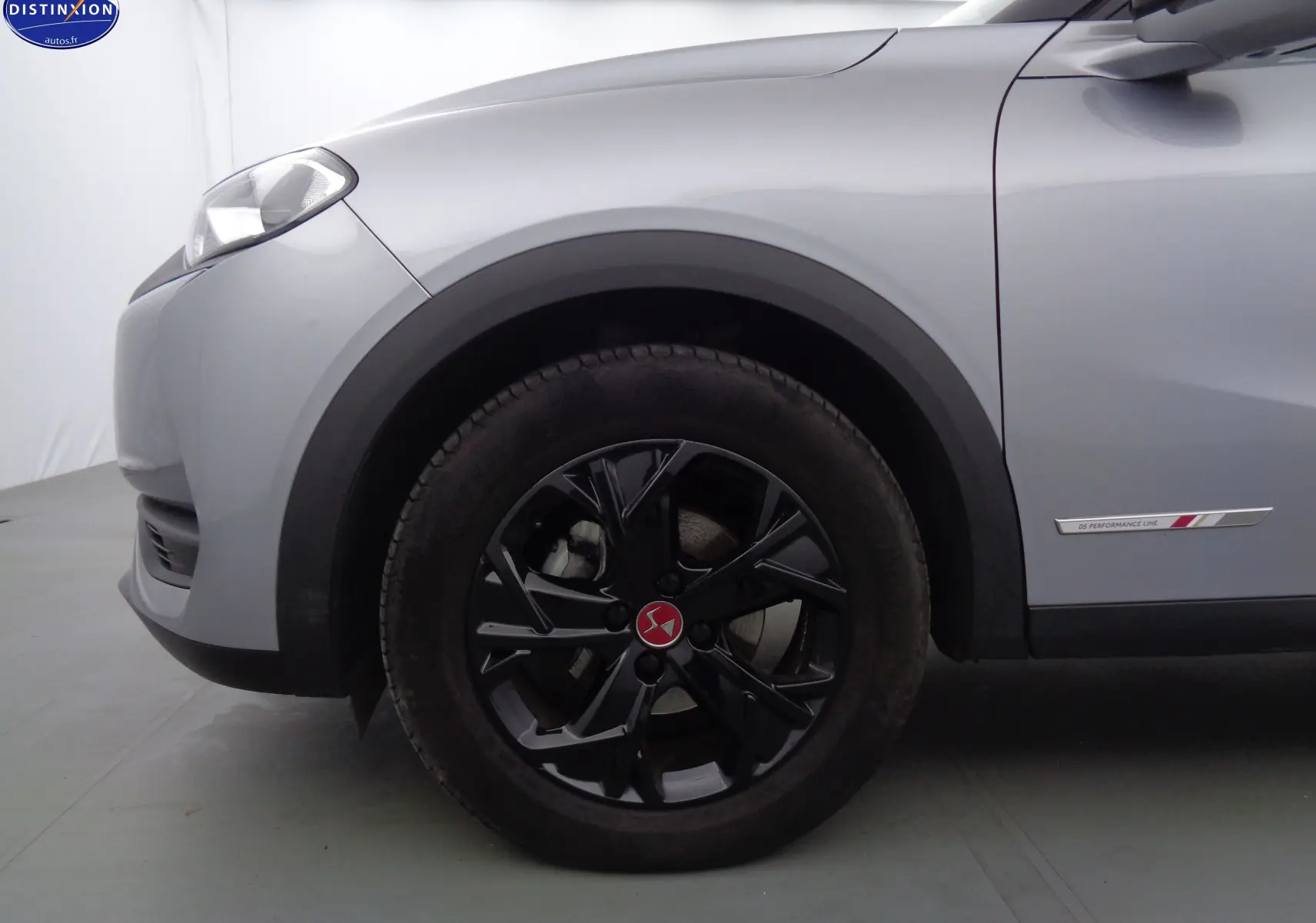 Gros plan sur la roue avant gauche noire et la carrosserie gris Artense d'un DS3 Crossback 1.5BLUEHDI 110 Performance Line.