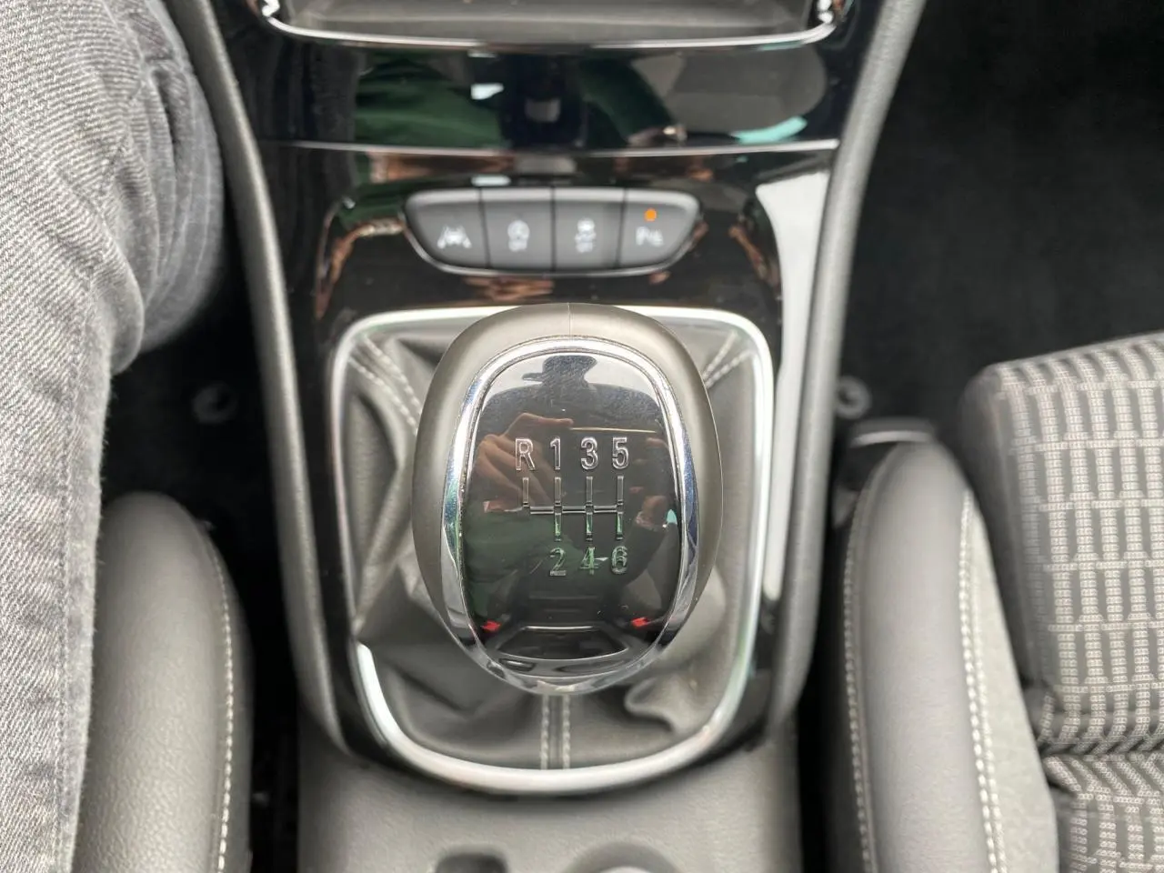 Le levier de vitesses manuel chromé de l'Opel Astra 2021, entouré de sellerie grise et console noire brillante.