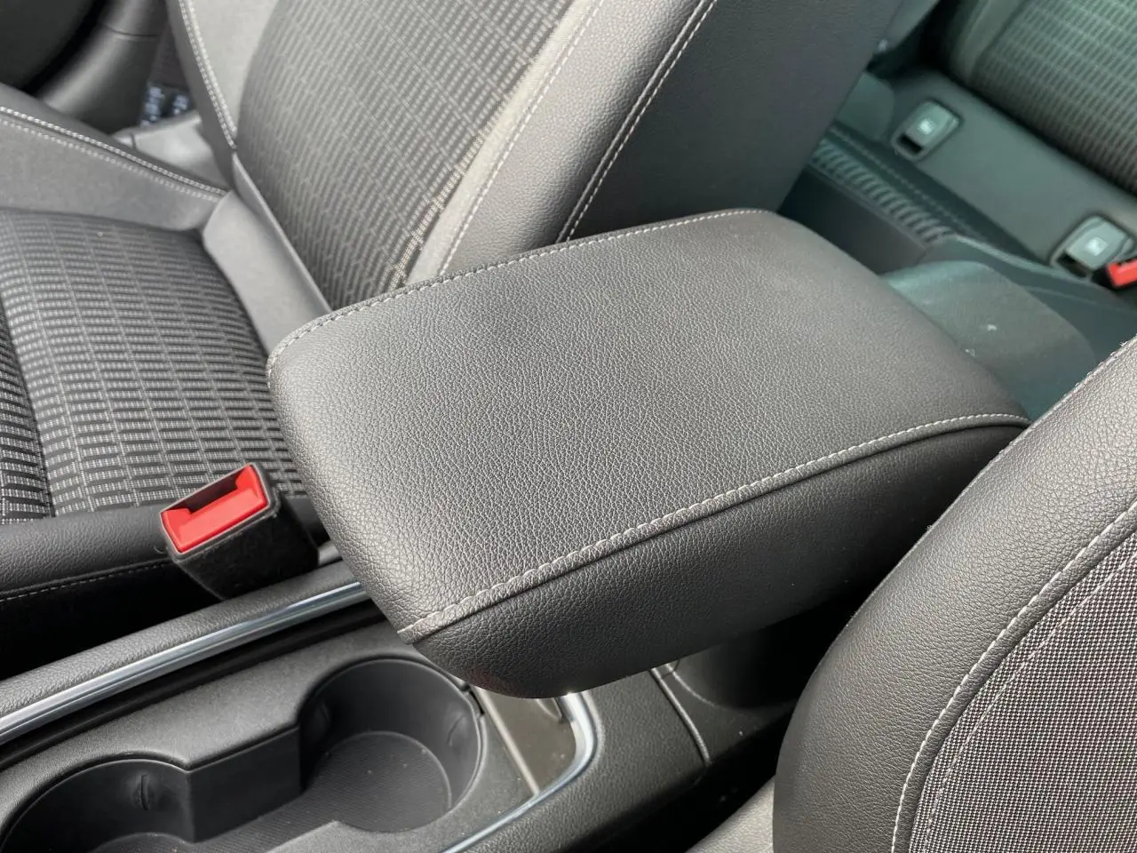 Gros plan sur l'accoudoir central en cuir noir et les sièges tissu gris de l'Opel Astra 2021.