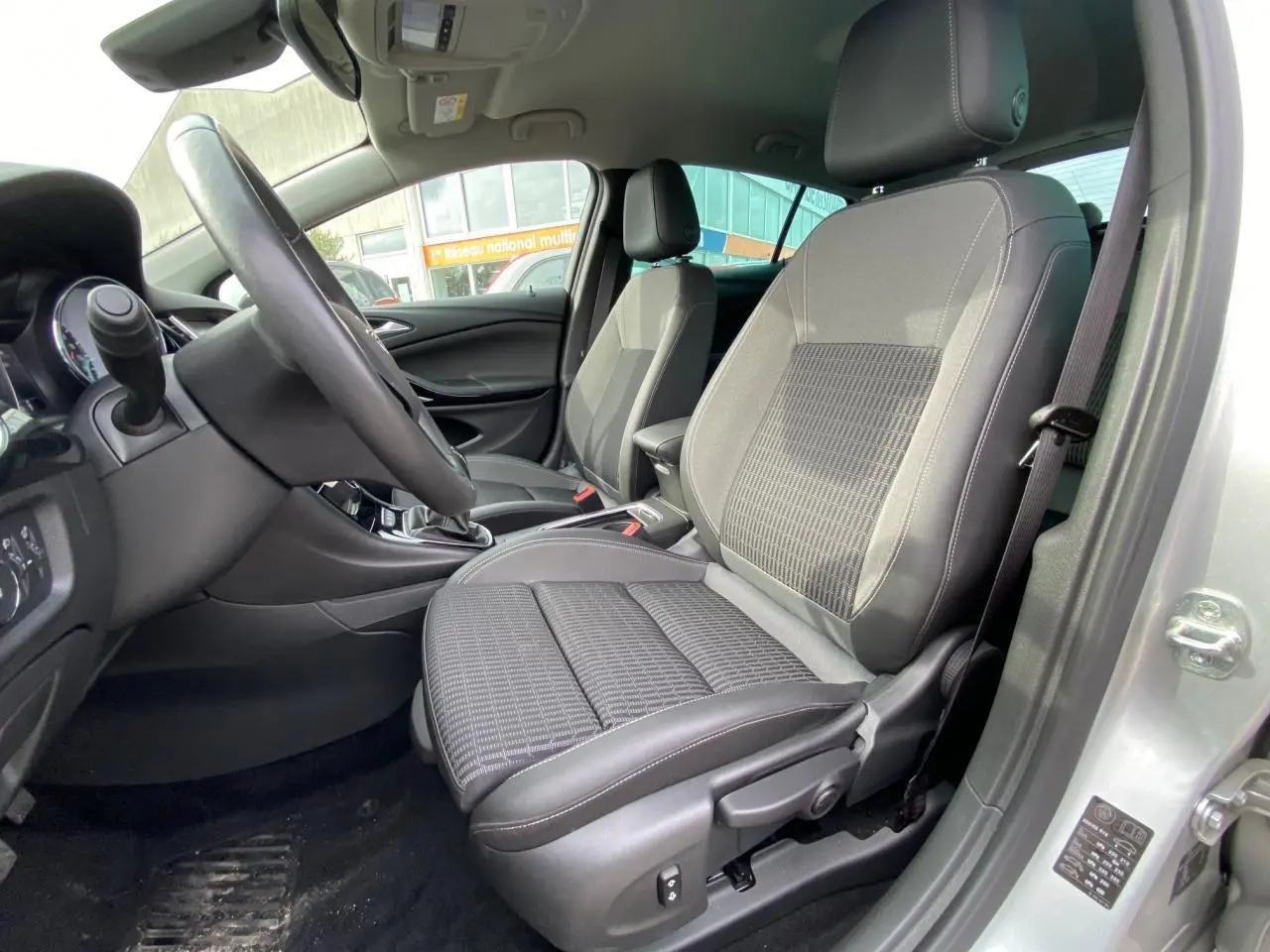 Intérieur de l'Opel Astra 2021 en Sovereign Silver, vue côté conducteur sur les sièges avant en tissu et cuir noir.