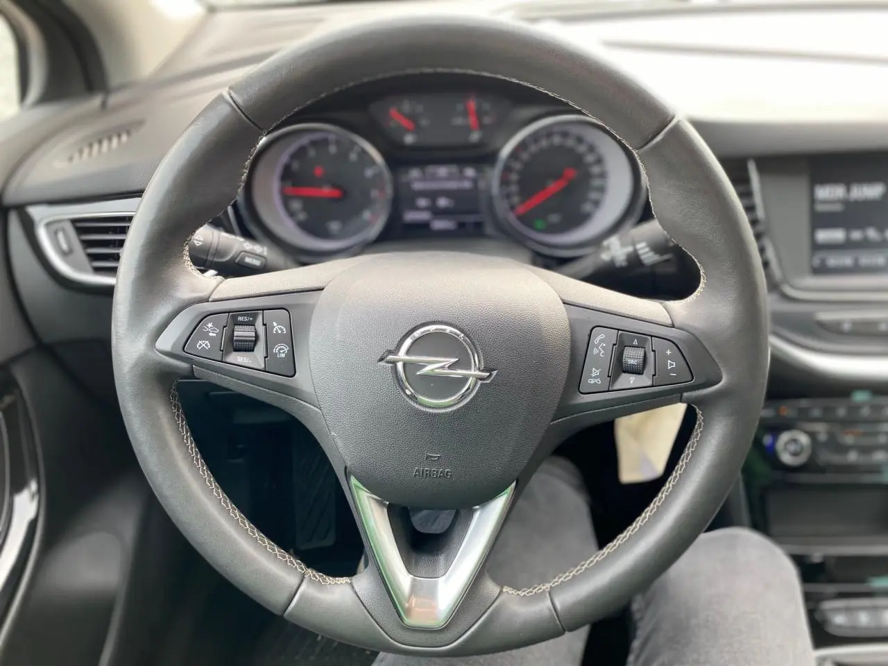 Volant en cuir de l'Opel Astra 2021 vu de face, avec commandes intégrées et tableau de bord en arrière-plan flou.