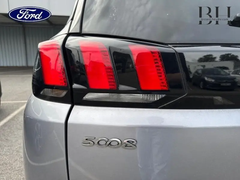 Gros plan sur le feu arrière droit et le logo 5008 d’un Peugeot 5008 gris Artense, arrière du véhicule visible.