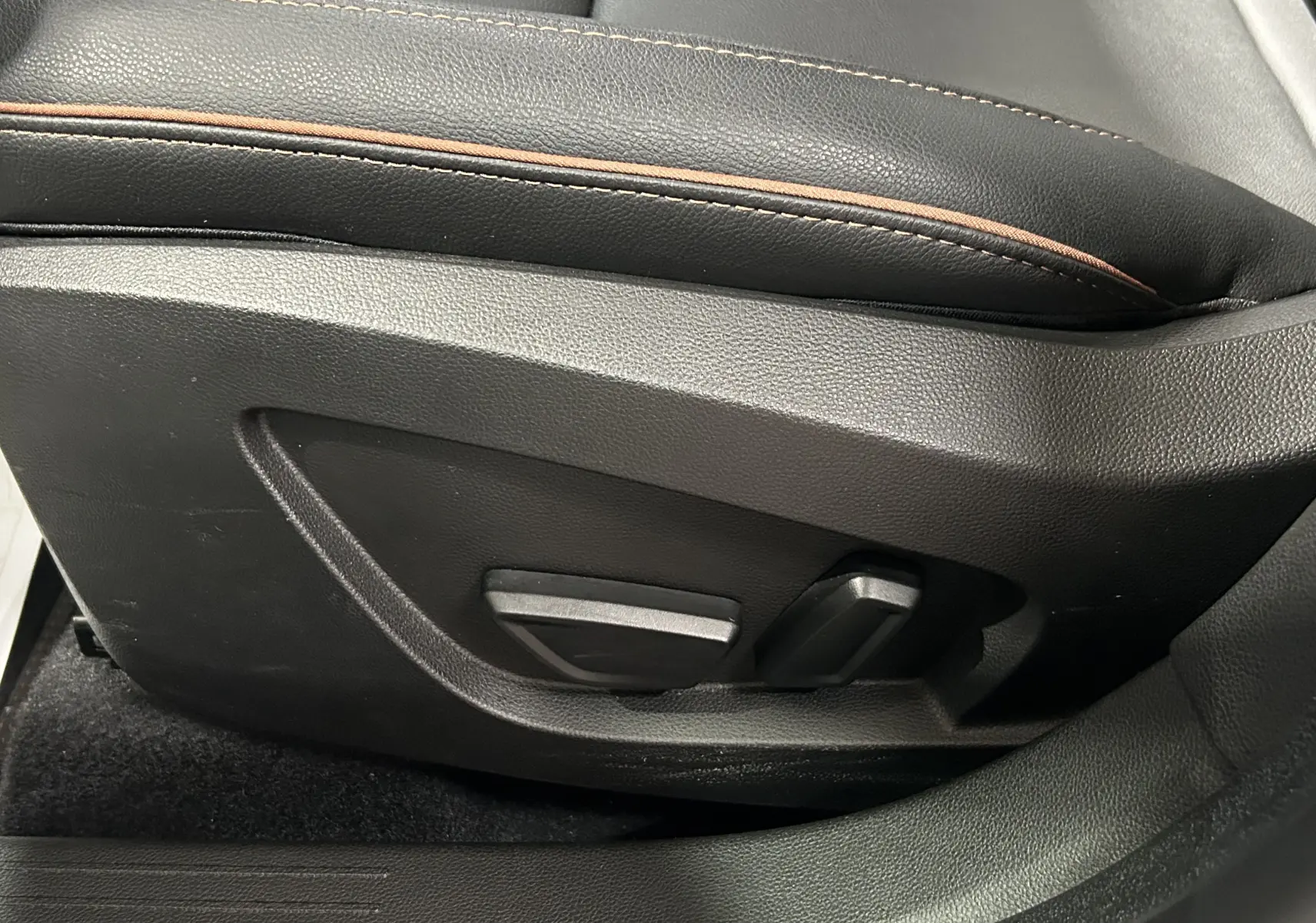 Détail des commandes de réglage électrique du siège conducteur en cuir noir avec surpiqûres marron du Renault Captur II Iconic 2022.