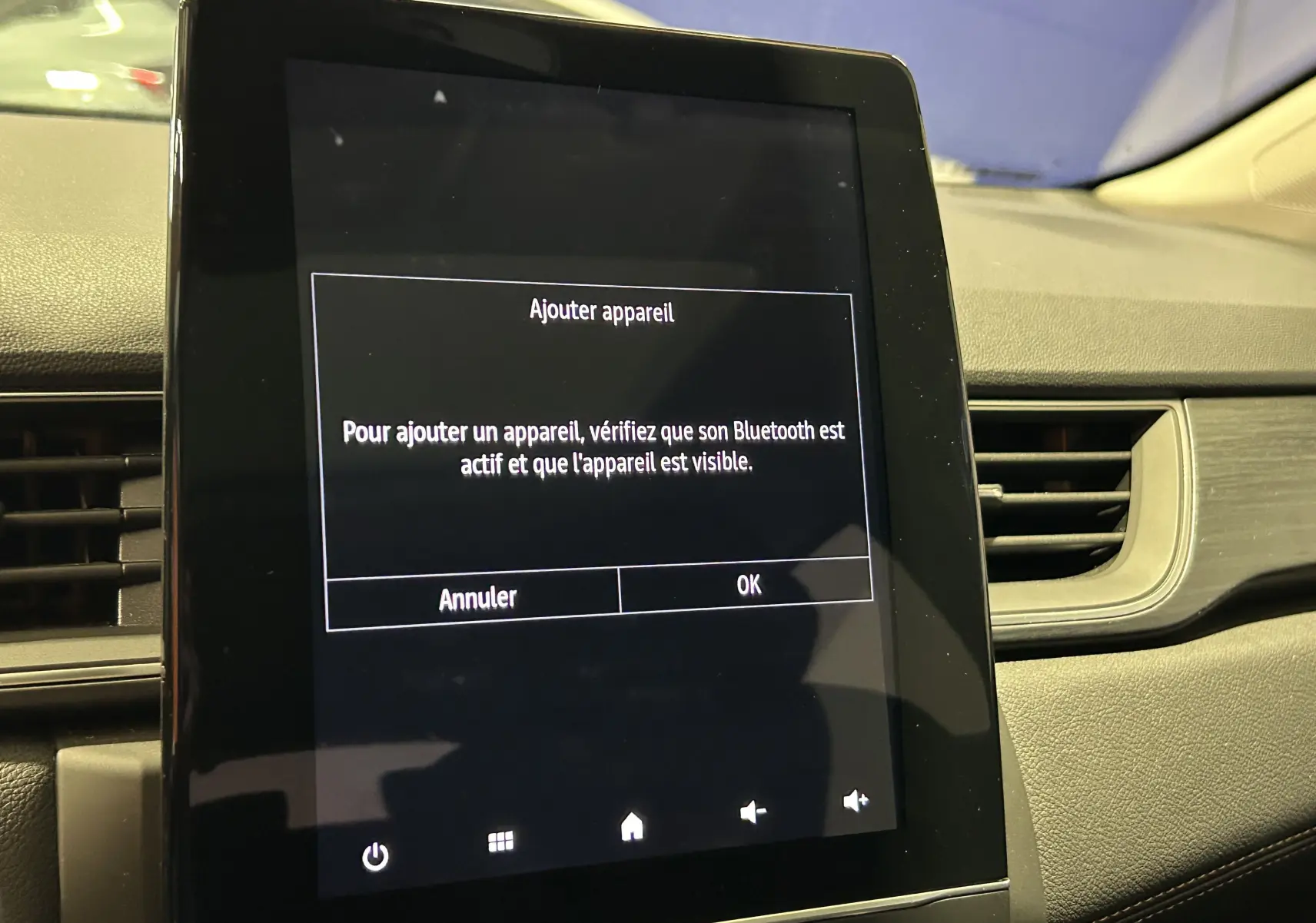 Écran tactile central affichant un message Bluetooth dans l'habitacle sombre d'une Renault Captur blanc nacré.