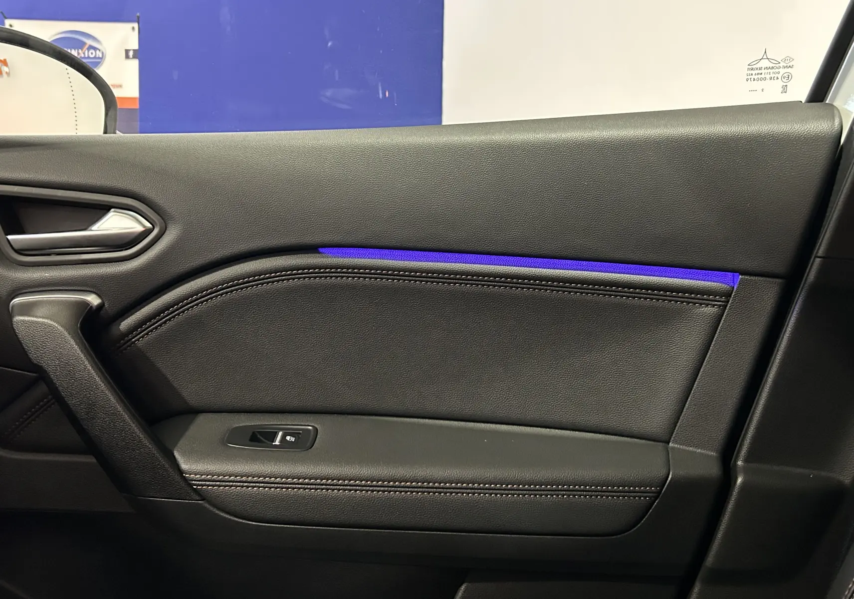 Gros plan sur la porte intérieure côté gauche du Renault Captur blanc nacré, avec éclairage d'ambiance bleu subtil.