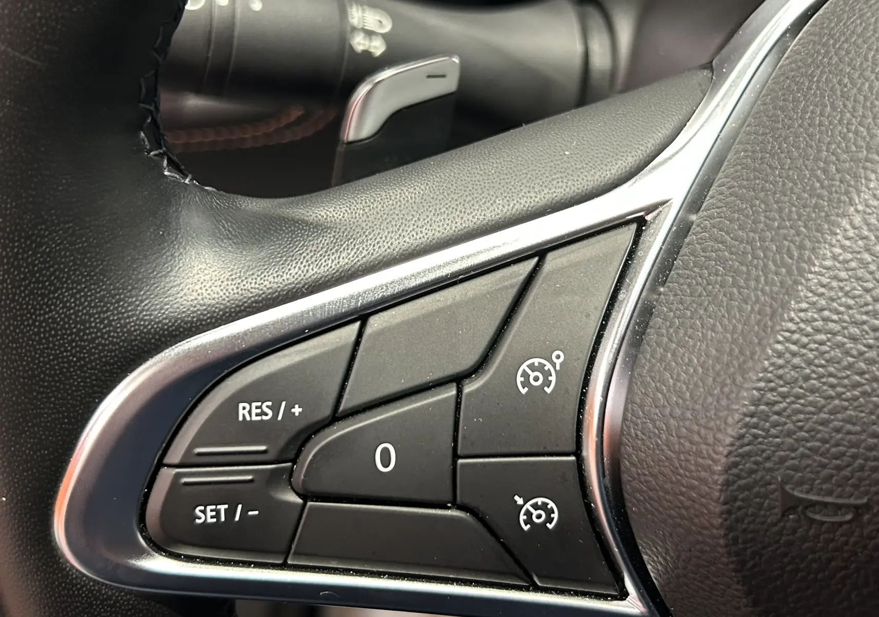 Gros plan sur les commandes de régulateur de vitesse au volant cuir du Renault Captur blanc nacré 2022.