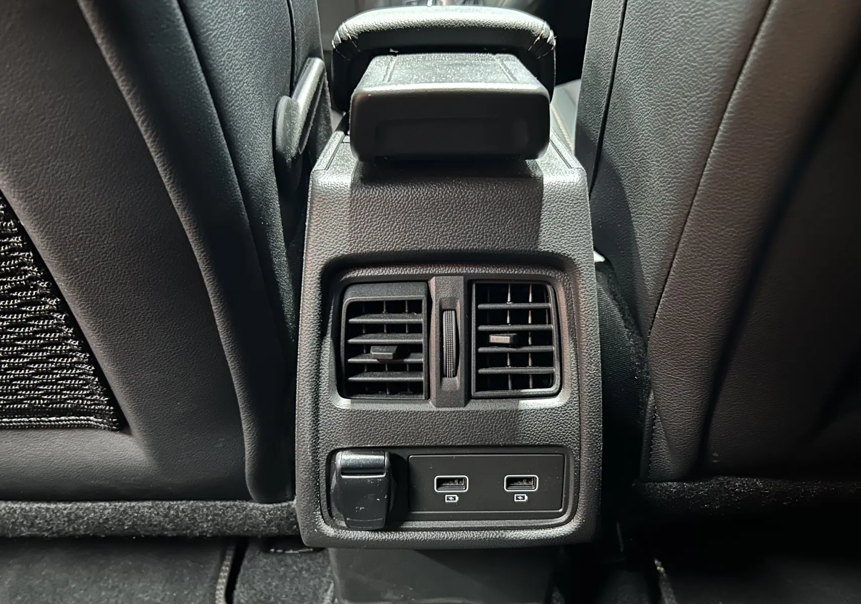 Vue rapprochée des aérateurs arrière et ports USB entre les sièges noirs du Renault Captur II Iconic blanc nacré.