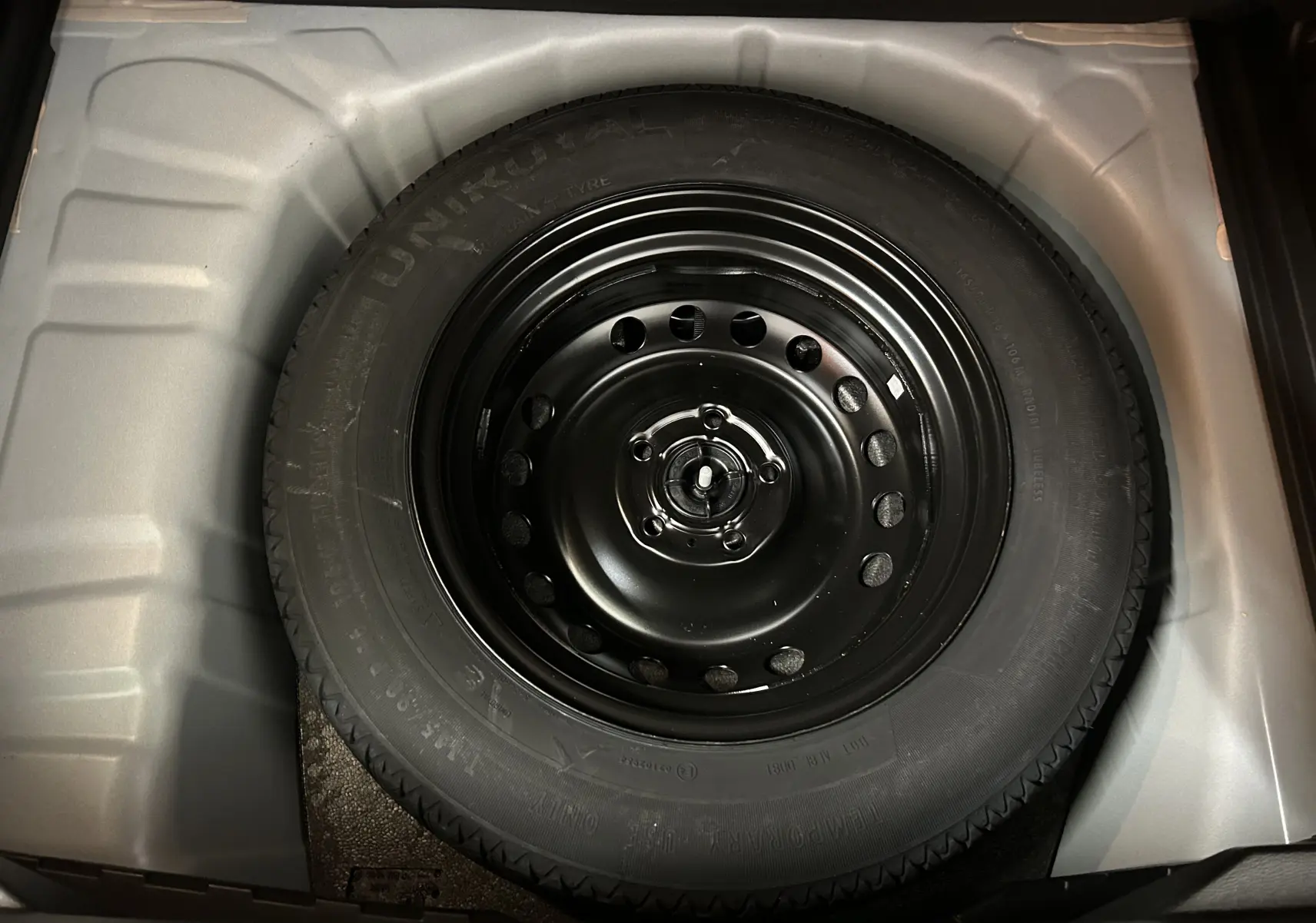 Roue de secours noire en gros plan dans le coffre d'un Renault Captur II Iconic blanc nacré 2022.