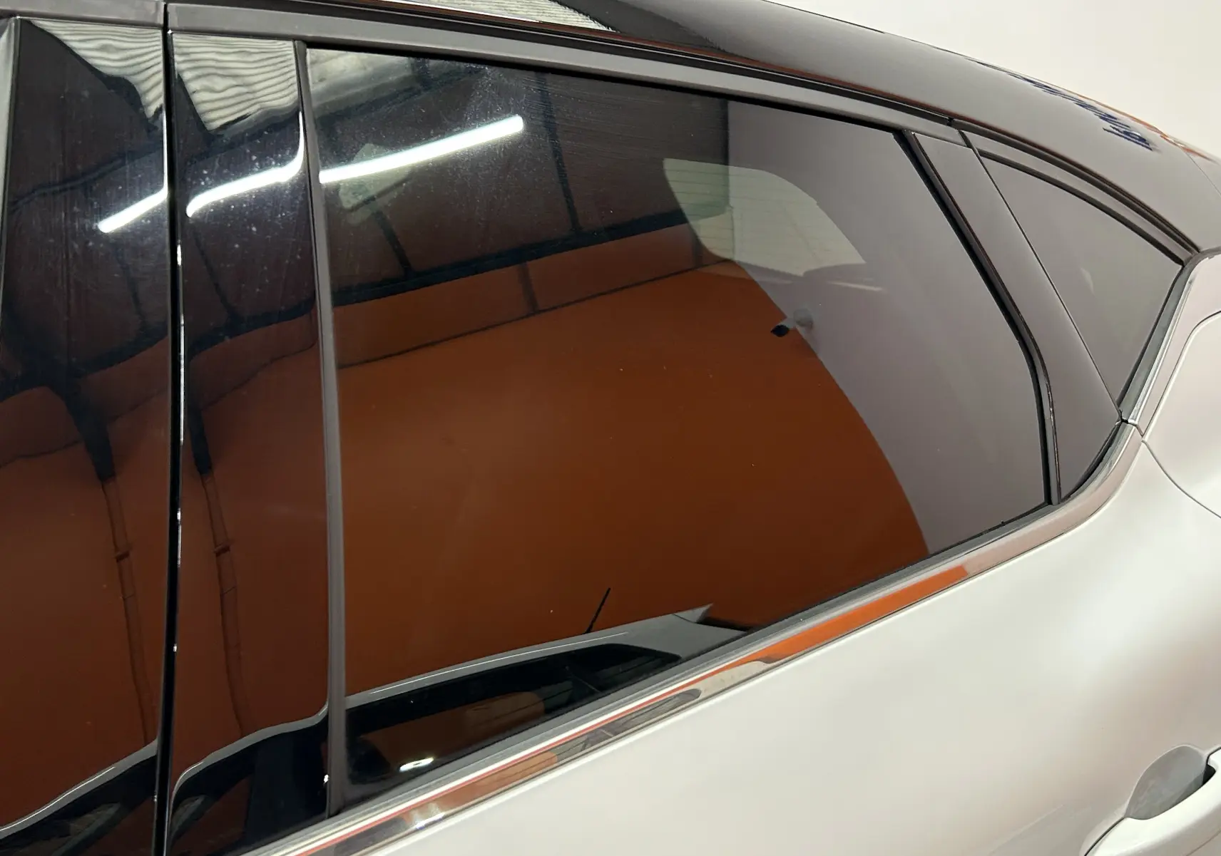 Gros plan sur la vitre arrière côté droit d'un Renault Captur blanc nacré avec cadre de fenêtre noir brillant.