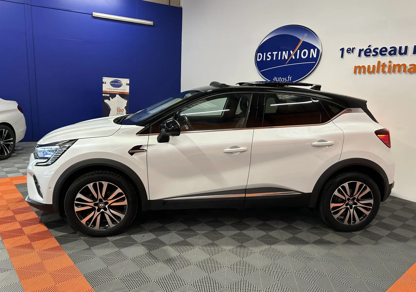 Profil côté gauche d'un Renault Captur blanc nacré 2022 avec toit ouvrant et jantes bi-ton en concession.