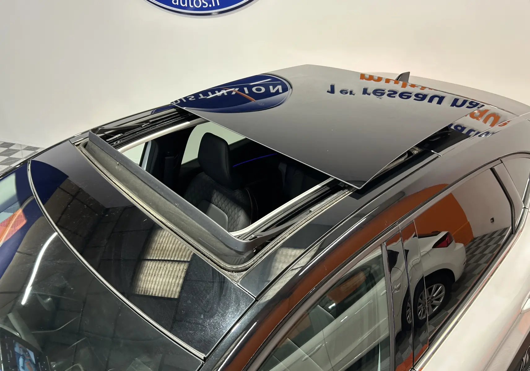 Vue plongeante sur le toit ouvrant noir d'un Renault Captur blanc nacré, avec intérieur cuir visible côté gauche.