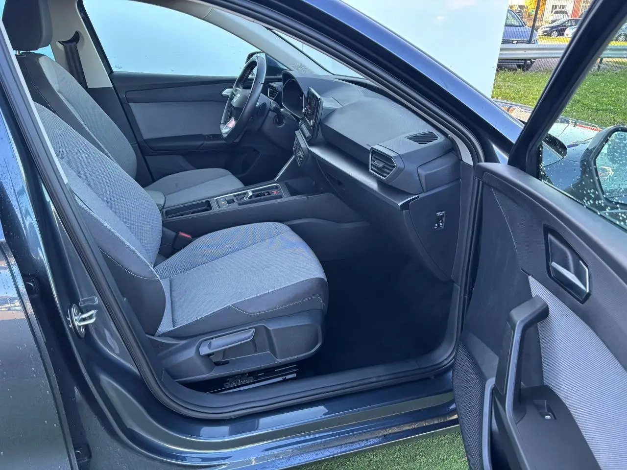 Vue intérieure côté passager avant de la SEAT Leon IV gris magnetic, montrant sièges tissu et tableau de bord moderne.