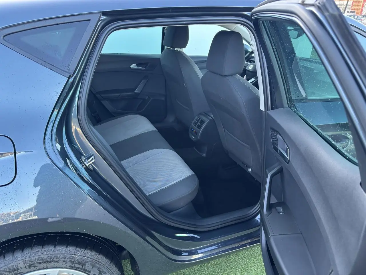 Vue intérieure arrière côté gauche d'une SEAT LEON gris magnetic 2024, montrant la banquette et les sièges avant.