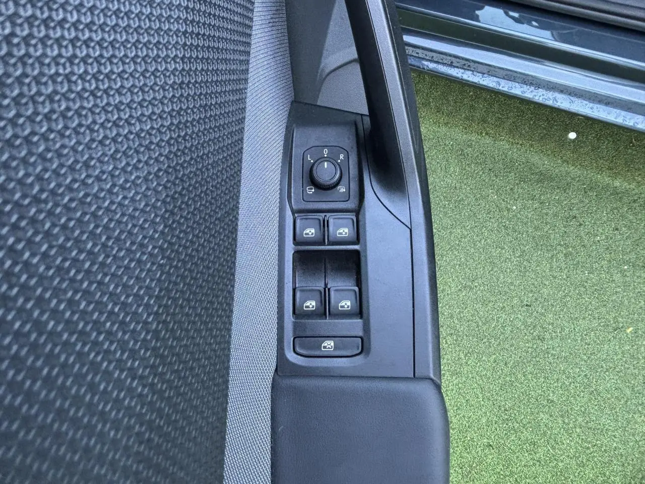 Gros plan sur les commandes des vitres et rétroviseurs côté gauche d'une SEAT Leon IV gris Magnetic, porte ouverte.