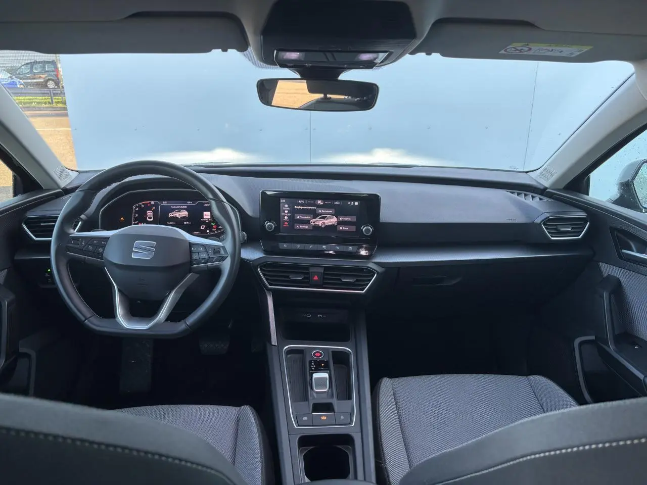 Vue intérieure avant du SEAT Leon IV gris Magnetic, avec tableau de bord digital et écran tactile central.