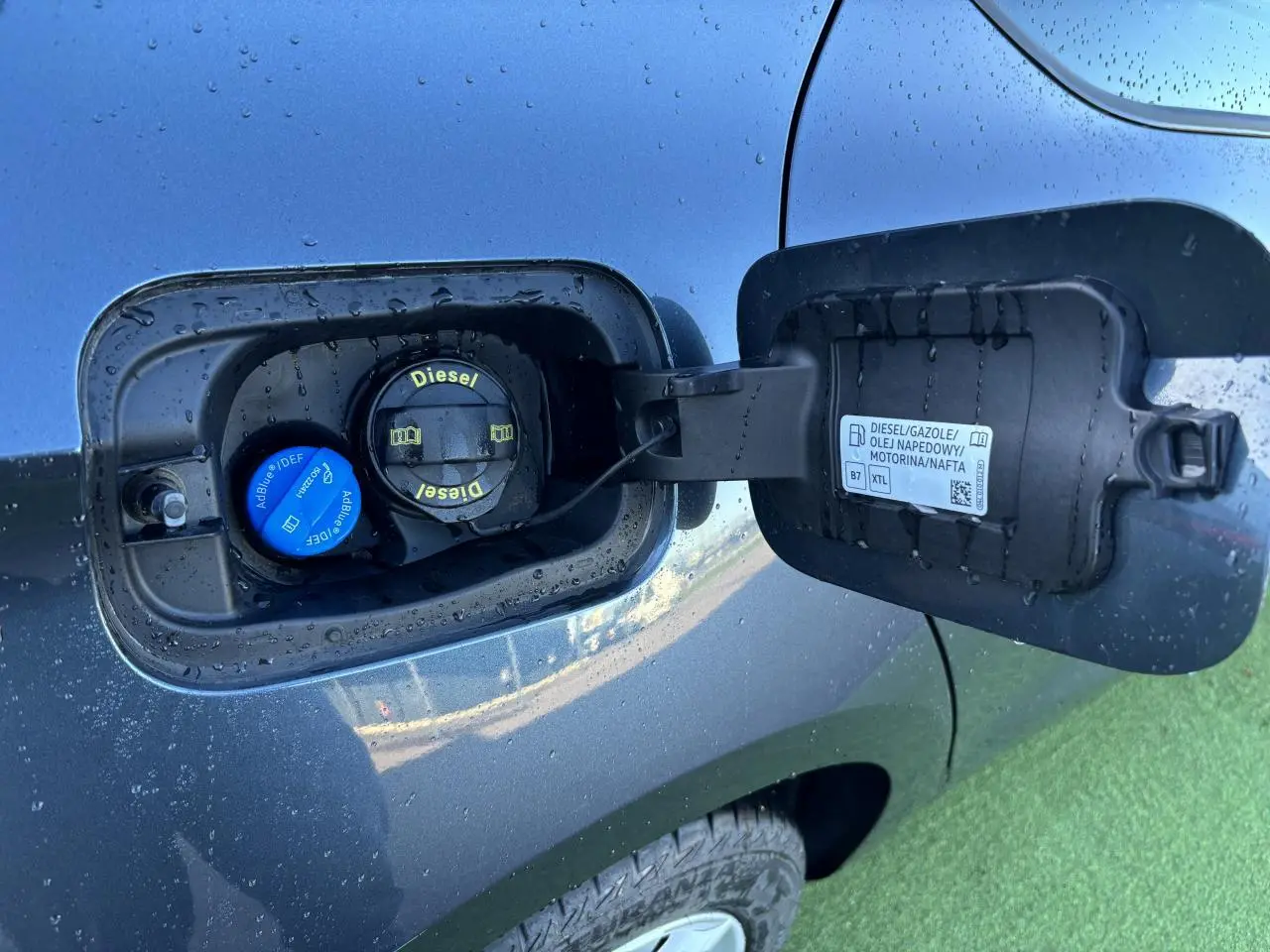 Gros plan sur la trappe à carburant côté gauche d'une SEAT LEON gris magnetic avec bouchons Diesel et AdBlue visibles.