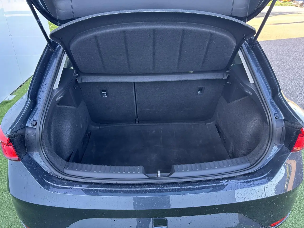 Coffre ouvert vu de l'arrière d'une SEAT LEON IV gris magnetic, montrant un espace de chargement vide et propre.