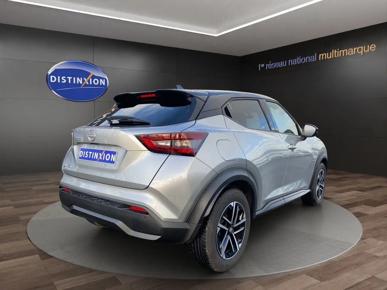 Vue 3/4 arrière droite du Nissan Juke gris perle avec toit noir et jantes alliage 17 pouces en showroom.