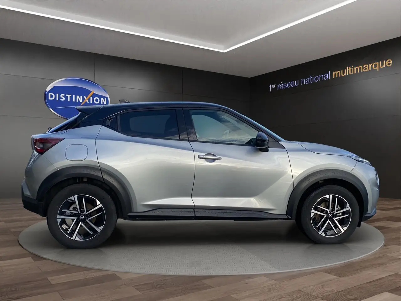 Vue latérale droite d’un Nissan Juke 2025 gris perle avec toit noir et jantes alliage 17 pouces en showroom.