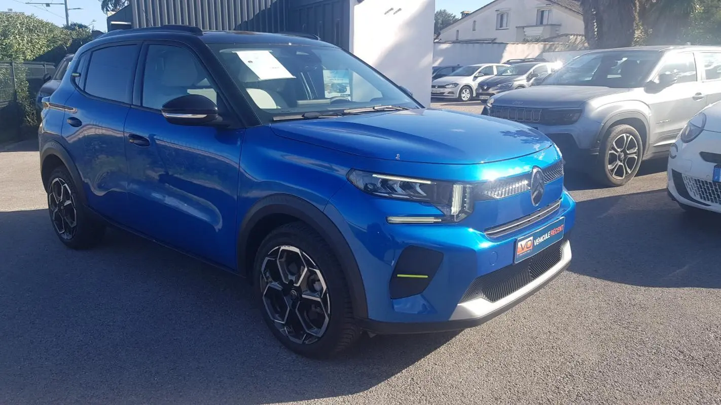 Vue 3/4 avant d'une Citroën C3 bleu foncé avec jantes alliage noires et barres de toit visibles en extérieur.