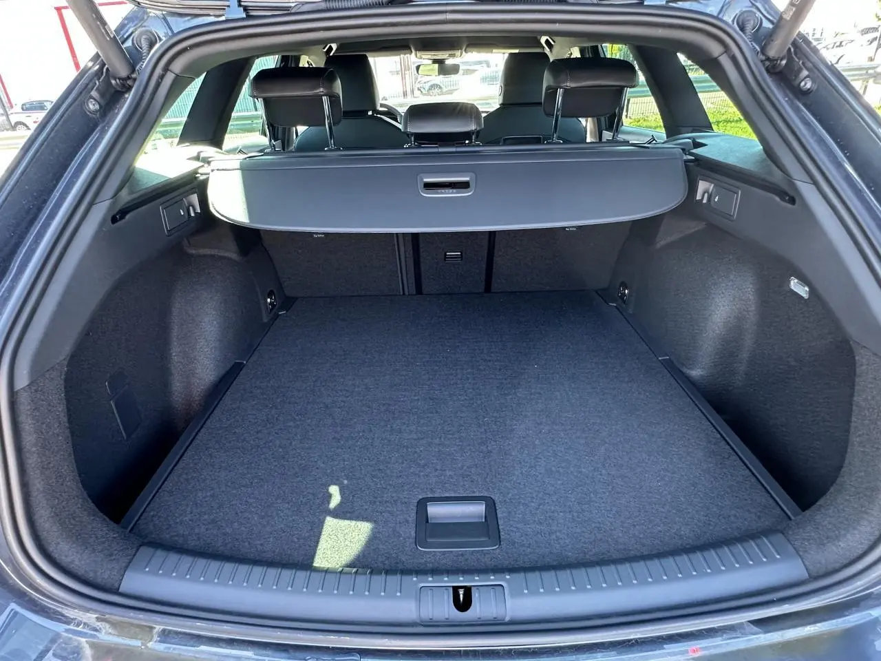 Coffre ouvert vu de l'arrière d'une CUPRA Leon Sportstourer gris magnétique, avec cache-bagages déployé.