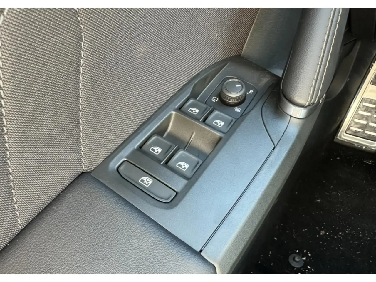 Gros plan sur les commandes de lève-vitres et rétroviseurs côté conducteur du CUPRA Leon Sportstourer gris magnétique 2025.