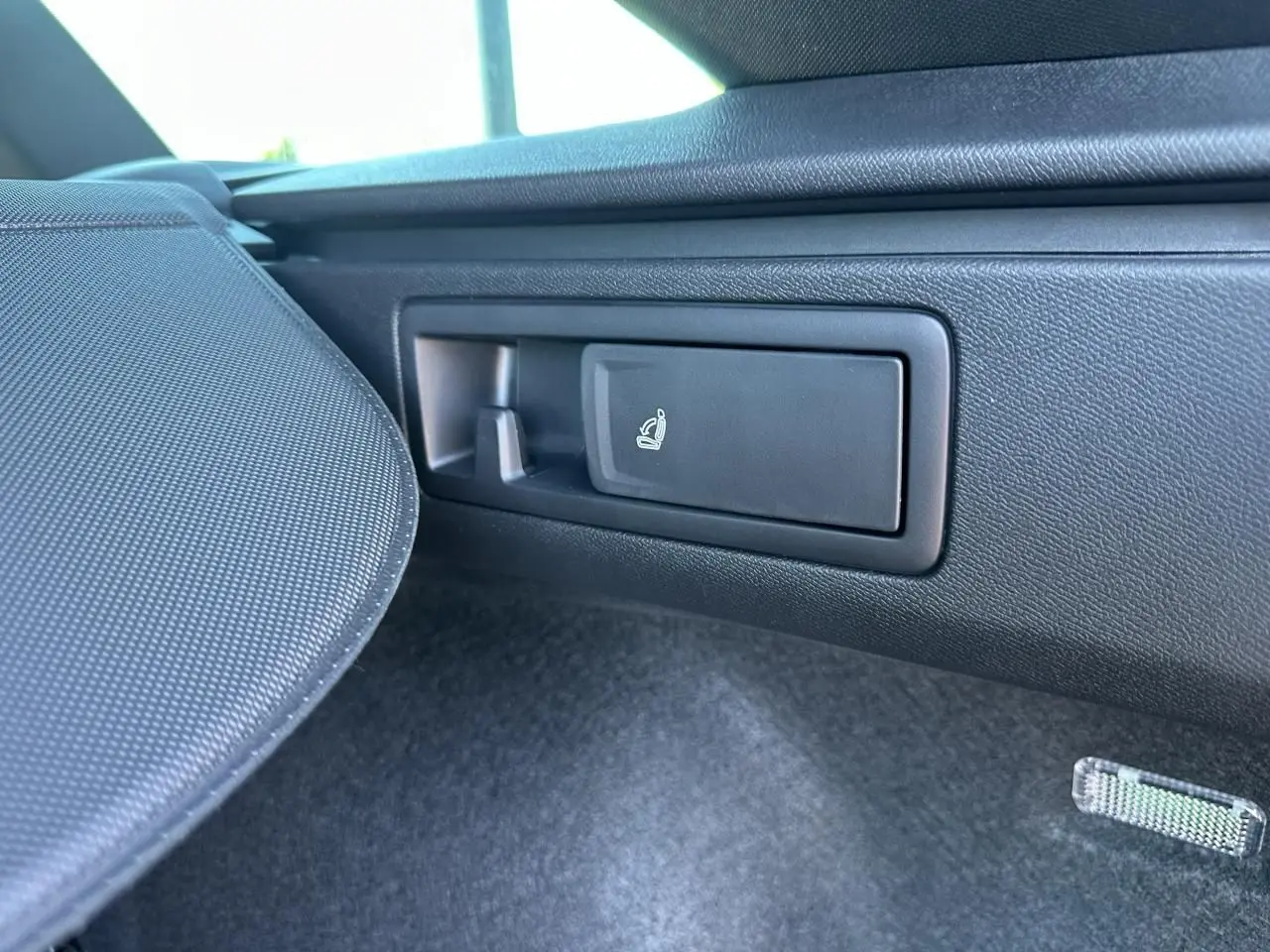 Gros plan sur la commande de rabattement des sièges arrière dans le coffre du CUPRA Leon gris magnétique 2025.