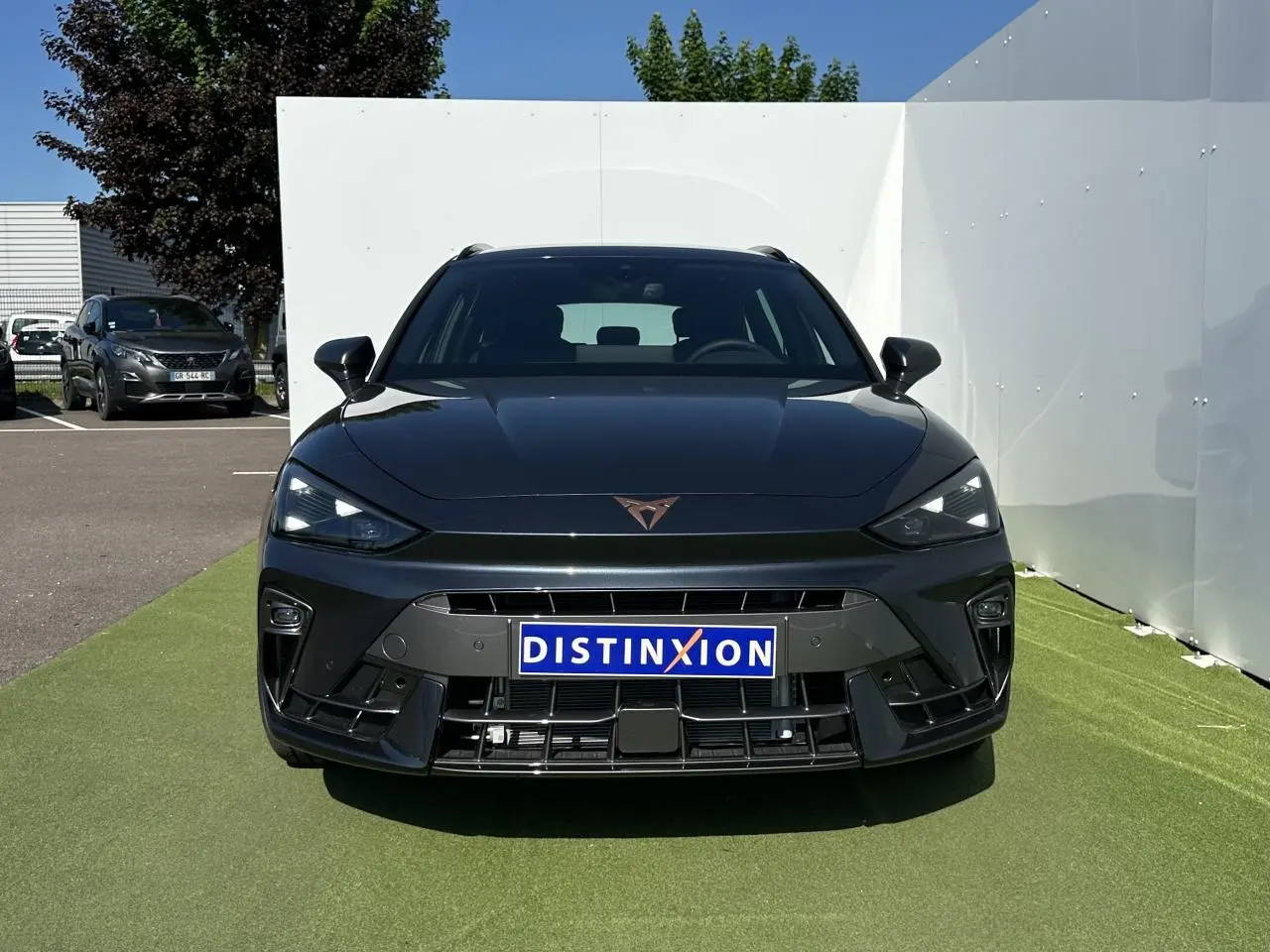 Vue frontale d'une CUPRA Leon Sportstourer gris magnétique avec logo CUPRA cuivré et calandre sportive noire.