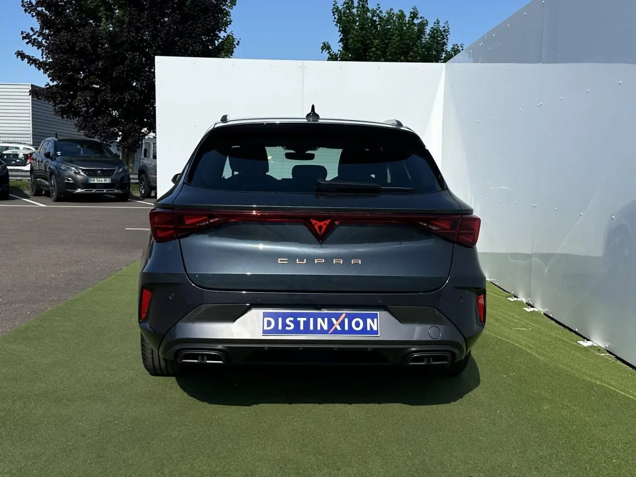 Vue arrière d'une CUPRA Leon Sportstourer gris magnétique avec signature lumineuse Tri-LED et double sortie d'échappement noire.