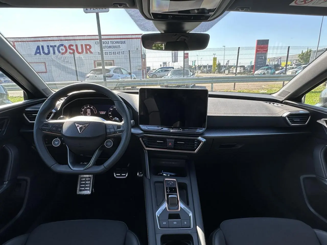 Vue intérieure frontale du poste de conduite noir du CUPRA Leon Sportstourer 2025 avec écran tactile central et volant Supersports.