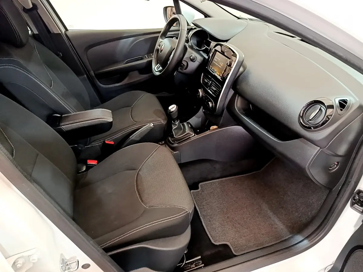 Intérieur de Renault Clio Business TCe 90 2019 blanc, vue côté conducteur montrant sièges noirs et tableau de bord avec écran tactile.