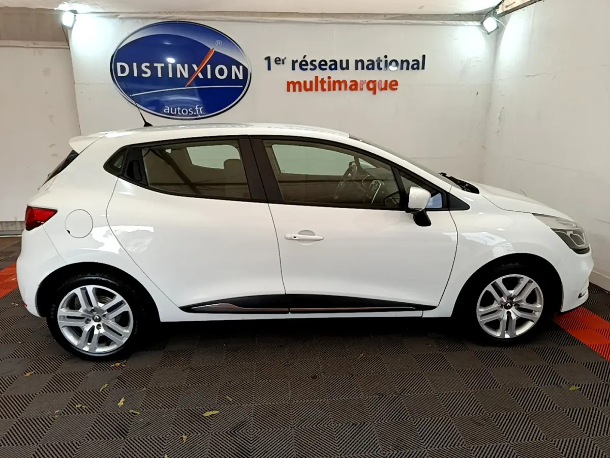 Profil côté gauche d'une Renault Clio Business TCe 90 blanche, avec jantes alliage et poignées de porte ton carrosserie.